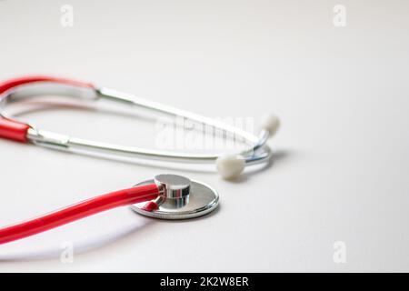 Stéthoscope rouge dans le bureau des médecins pour un examen cardio professionnel et un contrôle du pouls cardiaque sain par un cardiologue dans la salle de traitement clinique sur le bureau blanc comme équipement médical pour mesurer les params du corps Banque D'Images