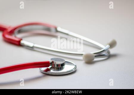 Stéthoscope rouge dans le bureau des médecins pour un examen cardio professionnel et un contrôle du pouls cardiaque sain par un cardiologue dans la salle de traitement clinique sur le bureau blanc comme équipement médical pour mesurer les params du corps Banque D'Images