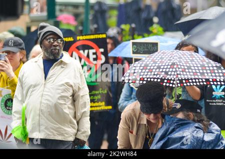Un homme qui marche dans la foule pendant le défilé annuel de Cannabis avec une bannière de slogan hors foyer Banque D'Images