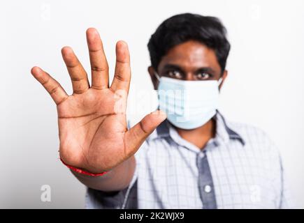 homme noir portant un masque de protection hygiénique chirurgical contre le coronavirus et levant le signe d'arrêt de main Banque D'Images