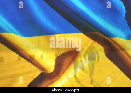 Composition double. Drapeau bleu et jaune de l'Ukraine et arrière-plan flou d'un couple marchant dans la ville un jour ensoleillé. Copier l'espace pour le texte. Banque D'Images