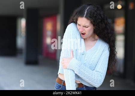 Femme souffrant de mal au coude dans la rue Banque D'Images