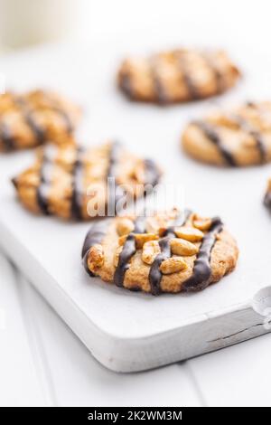 Biscuits aux pépites avec des arachides et des bandes de chocolat sur la table blanche. Banque D'Images