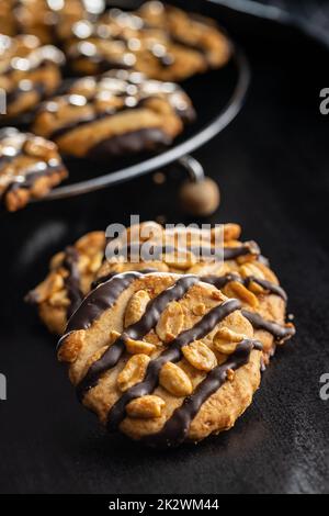 Biscuits aux pépites avec des arachides et des bandes de chocolat sur table noire. Banque D'Images