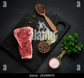 Morceau de viande de bœuf frais, steak de striploin sur fond noir, vue du dessus. Morceau de viande marbré Banque D'Images