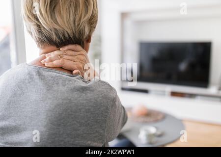 Femme âgée dans le salon avec douleurs au cou Banque D'Images