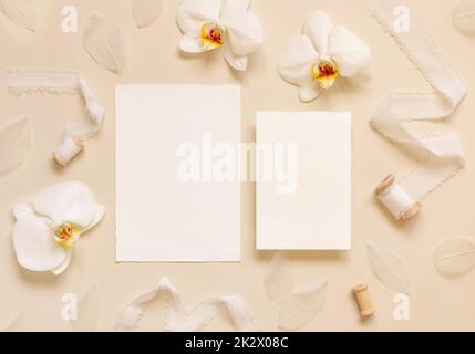 Cartes de mariage près de fleurs d'orchidées blanches et rubans de soie sur jaune clair, maquette de suite Banque D'Images