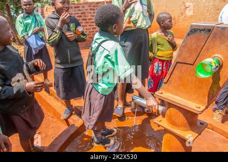 Des enfants de différents âges essayaient de recueillir de l'eau potable en Ouganda Banque D'Images