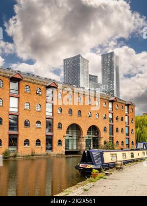 Le canal de Bridgewater le long de Merchants Warehouse, avec les quatre tours de la place Deansgate au loin. Banque D'Images