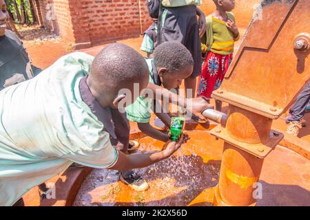 Des enfants de différents âges essayaient de recueillir de l'eau potable en Ouganda Banque D'Images