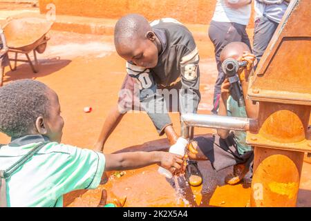 Des enfants de différents âges essayaient de recueillir de l'eau potable en Ouganda Banque D'Images