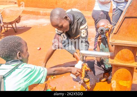 Des enfants de différents âges essayaient de recueillir de l'eau potable en Ouganda Banque D'Images