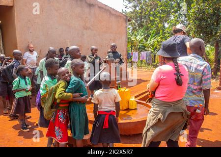 Des enfants de différents âges essayaient de recueillir de l'eau potable en Ouganda Banque D'Images