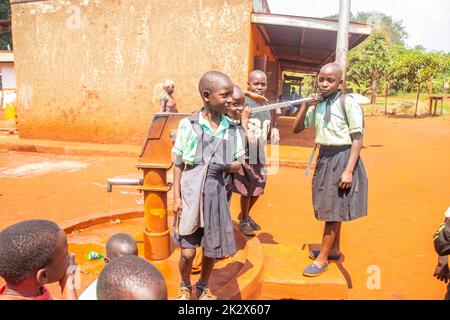 Des enfants de différents âges essayaient de recueillir de l'eau potable en Ouganda Banque D'Images