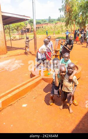 Des enfants de différents âges essayaient de recueillir de l'eau potable en Ouganda Banque D'Images