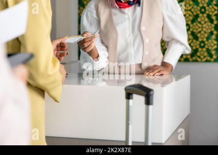 Une femme voyageur reçoit un billet d'embarquement de la part d'une femme officier au comptoir d'enregistrement de la compagnie aérienne. Banque D'Images