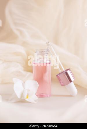 Bouteille de Dropper rose près de la fleur d'orchidée blanche sur fond jaune clair. Produit de beauté pour les soins de la peau Banque D'Images