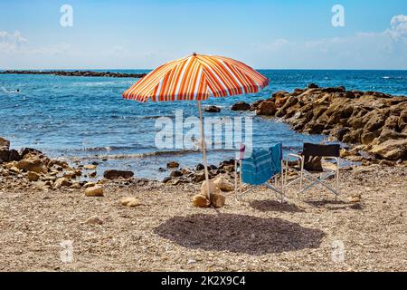 Parasol et deux chaises sur une plage de galets à Monterosso al Mare. Banque D'Images