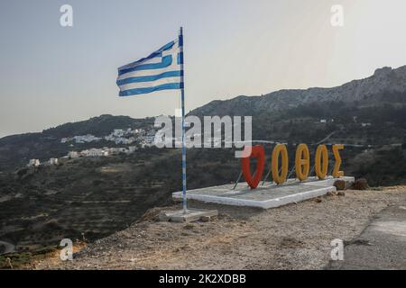 Karpathos, Grèce. 11th août 2021. Un drapeau grec soufflant et une construction avec le nom du village d'Othos dans l'île de Karpathos. Karpathos est la deuxième plus grande île du complexe grec Dodécanèse, dans le sud-est de la mer Égée. L'île de Karpathos conserve toujours son mode de vie traditionnel, comme le village 'Olympos', où les autochtones portent encore les costumes traditionnels. (Photo de Maria Makraki/SOPA Images/Sipa USA) crédit: SIPA USA/Alay Live News Banque D'Images