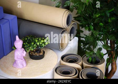 Plusieurs tapis en caoutchouc roulé pour le yoga ou la remise en forme en beige et gris et blocs de mousse pour le sport en studio. Banque D'Images