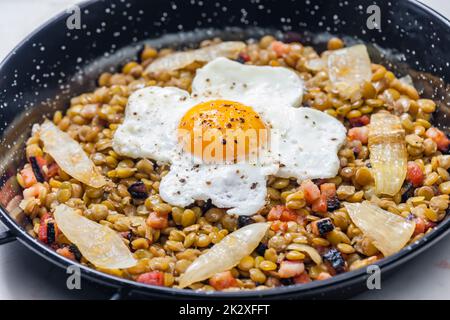 lentilles à la viande fumée et à l'oignon servies avec des œufs frits Banque D'Images