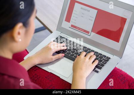 Jeune femme asiatique en robe rouge dactylographiant sur ordinateur portable clavier, s'inscrivant pour l'application de rencontres en ligne sur le site Web. Banque D'Images