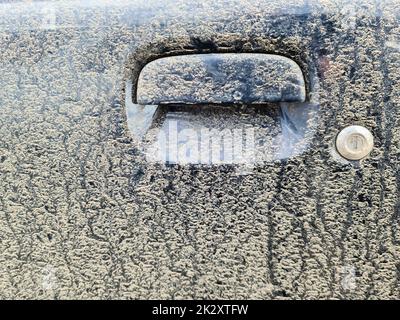 Une poignée de voiture très sale à une porte de voiture noire. Banque D'Images