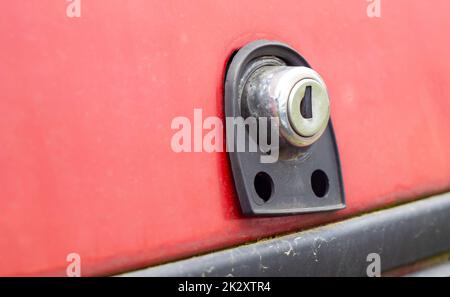 Ancienne serrure de coffre de voiture. Détails de verrouillage du coffre. Gros plan d'une poignée pour ouvrir la porte arrière d'une voiture rouge vintage. Banque D'Images