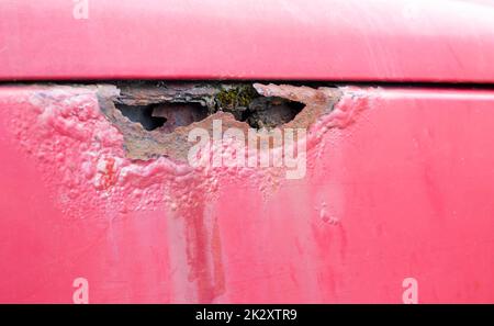 Aile rouillée. Corrosion de la carrosserie d'une vieille voiture rouge après l'hiver. Influence des réactifs en hiver sur le corps d'un véhicule non protégé. Dommages du côté gauche. Banque D'Images