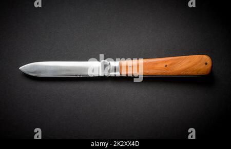 Couteau de poche traditionnel en bois sur fond noir Banque D'Images