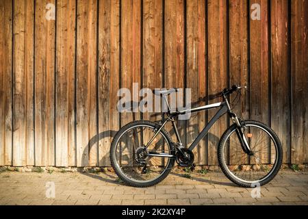 Vélo de montagne sport moderne appuyé contre un mur en bois brun Banque D'Images