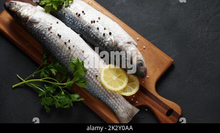 Fruits de mer poisson-mulet frais à la chaux, aux herbes et aux épices sur fond sombre. Banque D'Images