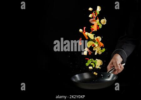 Croiser l'homme anonyme en lançant des légumes coupés dans le pan Banque D'Images