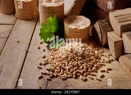 Bois de chauffage avec briquettes de biocarburants et granulés de bois sur table Banque D'Images