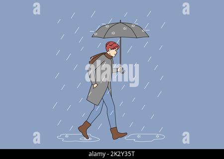 Homme avec un parapluie marchant sous la pluie Banque D'Images