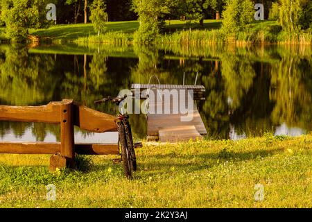Vélo de sport moderne appuyé contre un banc en bois au bord du lac Banque D'Images
