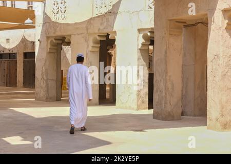 Vue arrière sur un arabe non identifié portant des vêtements blancs traditionnels du Moyen-Orient marchant dans la vieille ville. Banque D'Images