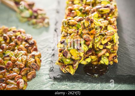 Verser du miel sur des bonbons traditionnels à la pistache enrobés de sucre. Dessert oriental égyptien généralement mangé lors de la « Fête d'anniversaire du prophète Mahomet ». Banque D'Images