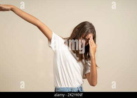 Jeune fille hispanique d'adolescence frappant une pose drôle sur un fond beige studio Banque D'Images