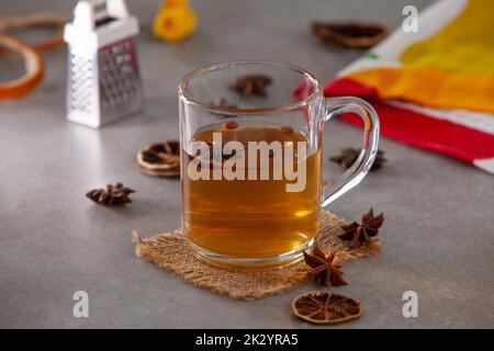 Un mug avec thé chaud à l'anis étoilé (Ilicium verum) avec des graines et un râleur en arrière-plan Banque D'Images