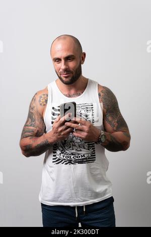 Téléphone mode décontracté blanc jeune gars blanc style de vie tatouage, concept tshirt de vêtements et de la barbe vers le haut, inscription en coton. Voir les meilleurs articles pour adultes, Banque D'Images