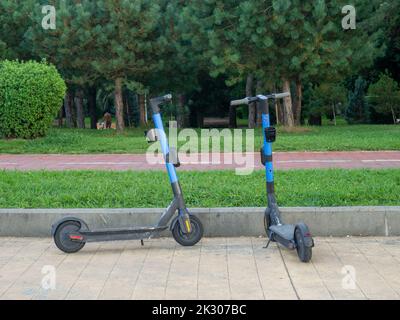 Scooters électriques sur l'allée dans le parc de la ville. Véhicule moderne. Transport à deux roues. Divertissement à la station. Banque D'Images