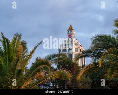 Bâtiment haut inhabituel. Maison avec tour et horloge. Architecture moderne de la Géorgie. Batumi. Le bâtiment en hauteur est visible parmi les arbres. Banque D'Images