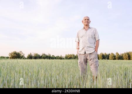 Agriculteur senior debout avec les mains dans les poches à la ferme Banque D'Images