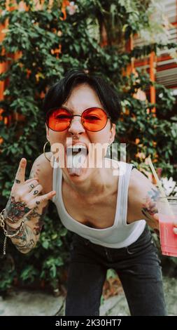 Femme hipster collant hors de la langue gestant le signe de corne Banque D'Images