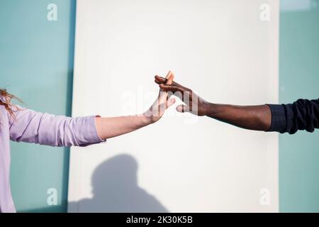 Homme et femme avec les doigts entrelacés devant le mur Banque D'Images