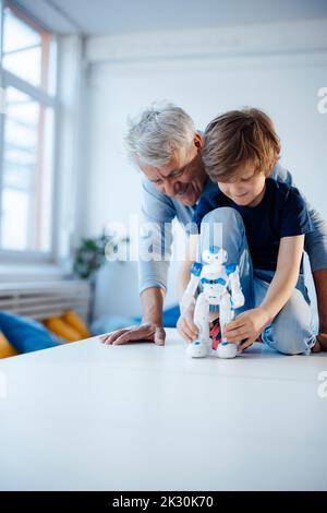 Boy playing with robot model by grandfather at home Stock Photo