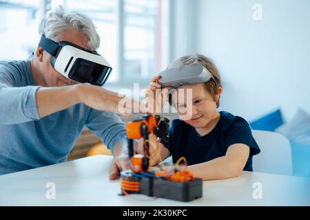 Garçon examinant le modèle de robot par grand-père avec des lunettes VR à la maison Banque D'Images