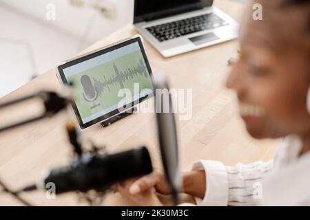 Sound wave on tablet screen with freelancer broadcasting podcast Stock Photo