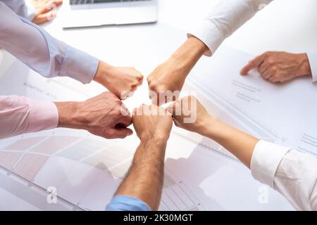 Hands of business colleagues bumping fists over table in meeting Stock Photo